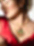 A woman in a red blouse wears a gold necklace with a green fan-shaped pendant, her hair adorned with flowers, shown against a bright background.