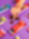A partially unwrapped Fancis Premium Dark Chocolate bar (50% cocoa) on a purple background, with scattered coffee beans and cocoa powder.