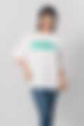 Close-up of a woman in a white T-shirt reading 'Talented' in green, styled with denim jeans
