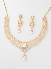 Smiling woman in a white traditional outfit wearing an intricate gold and diamond necklace with matching earrings, set against a warm golden background.