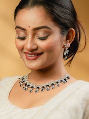 Gold bangles with intricate circular diamond settings placed on a light fabric near an orange rose.