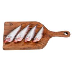 Four fresh raw fish laid out on a wooden cutting board, ready for cooking.