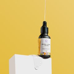 A sleek bottle of face serum with a dropper, displayed on a white pedestal against a vibrant yellow background.