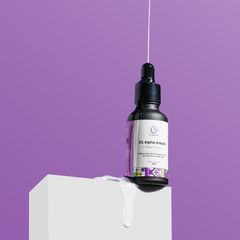 A sleek bottle of face serum with a dropper, displayed on a white pedestal against a vibrant purple background.