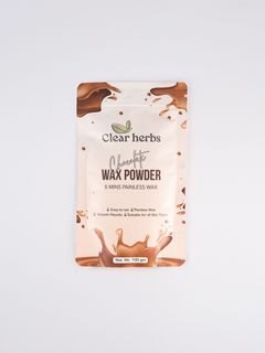 A woman in a green T-shirt sits on a dark armchair holding a green-themed anime poster, with additional anime posters on a red wall and a rattan lamp beside her.