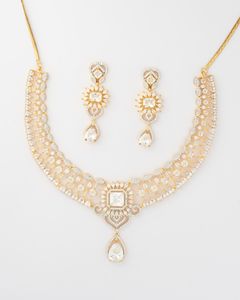 Intricate gold necklace with a net-like diamond design and matching drop earrings, displayed on a white background.