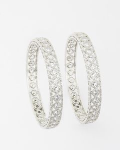 Intricately designed silver bangles with circular diamond patterns displayed on a white background.