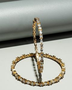 Elegant gold and diamond-studded hoop earrings with marquise and baguette-cut stones, artistically displayed against a modern backdrop.